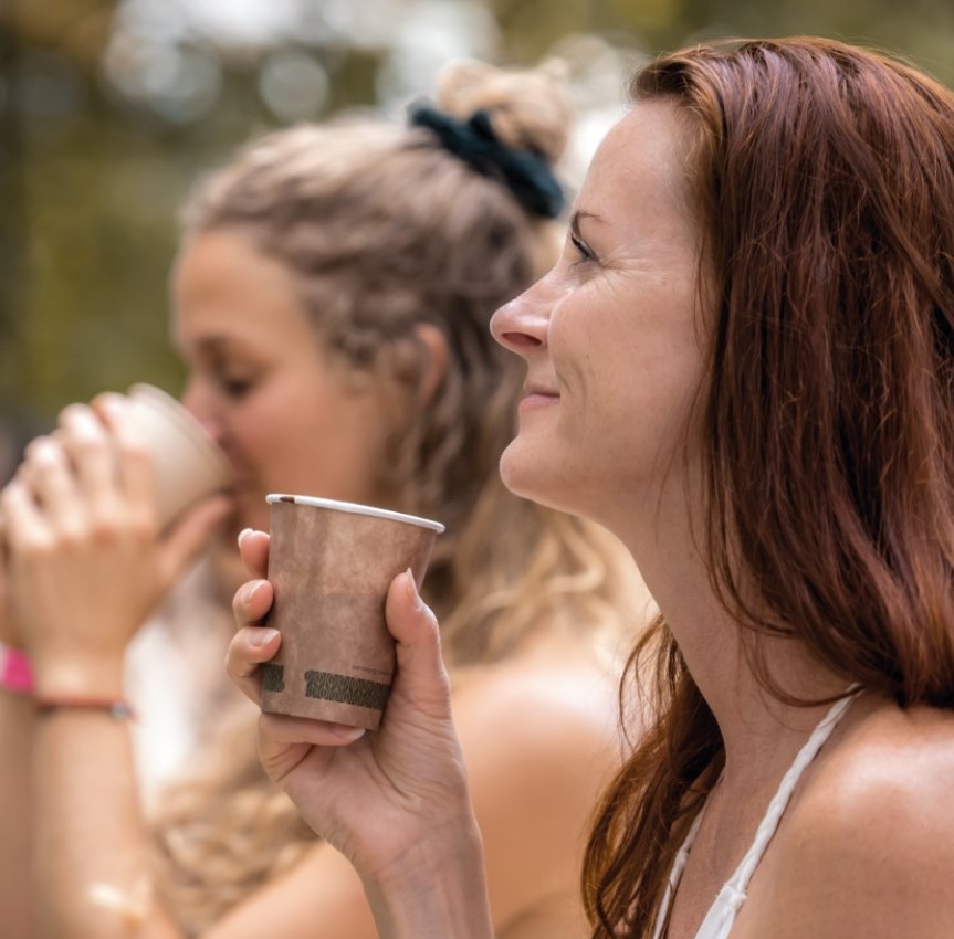 Zwei Frauen mit geschlossenen Augen genießen achtsam eine Tasse zeremoniellen avaCao – ein Moment der Verbindung und Präsenz.