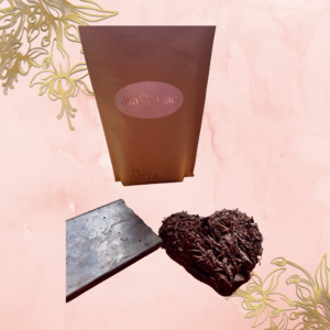 Naturfarbene Kraftpapierverpackung mit rosa Aufkleber darauf goldene Aufschrift „avaCao Shiva“. Darunter Ritualcacao Shiva - The Peruvian Chuncho als Cacao-Block und Cacao-Herz daneben.